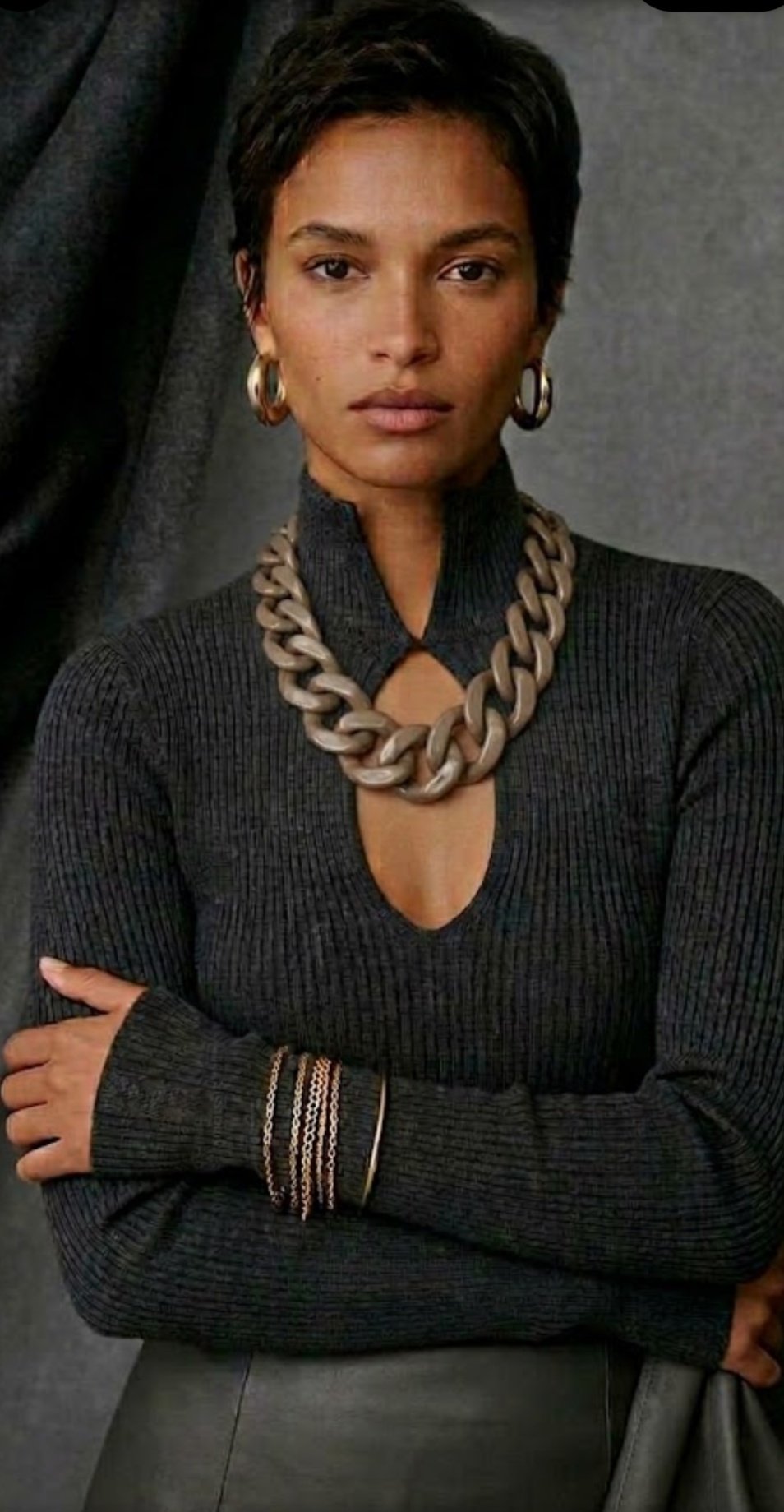 Short-haired model wearing a gray statement necklace with charcoal knitwear
